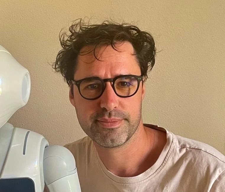 Sébastien Petit, fondateur du studio SebaNeoWave, à côté d'un robot humanoïde Pepper